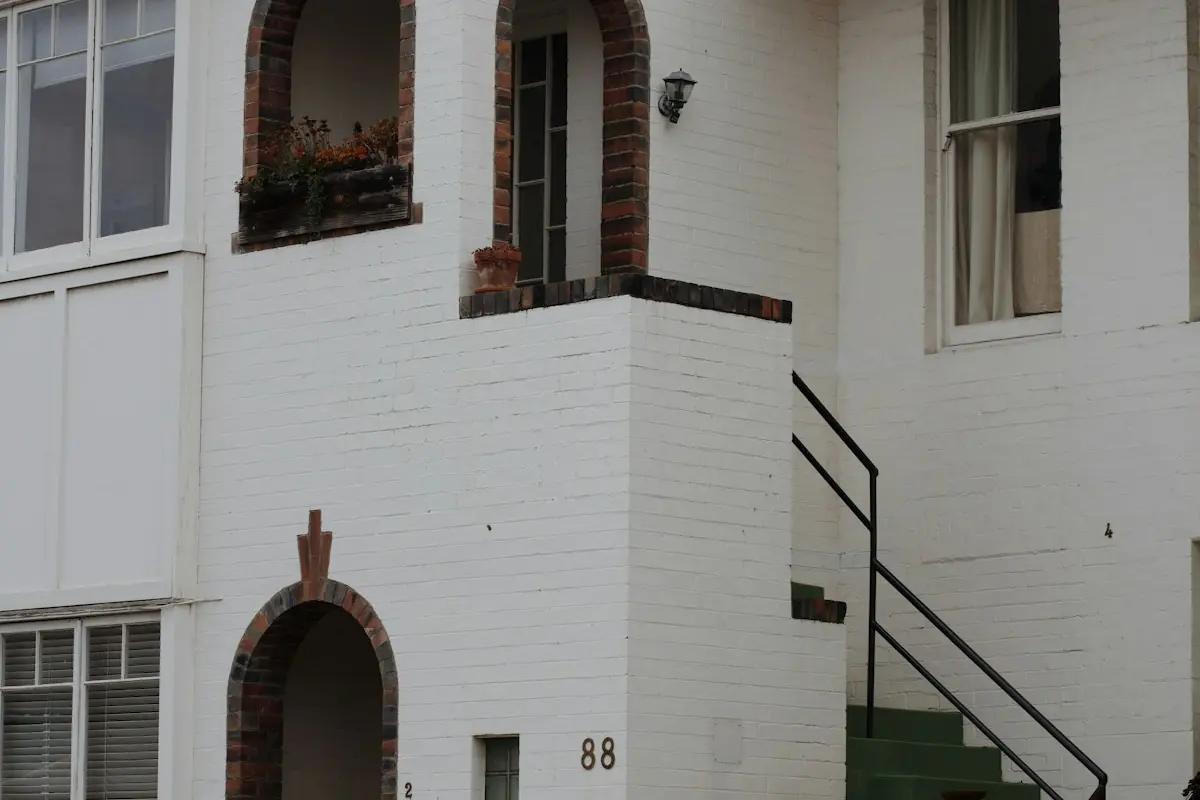 A white brick apartment building with arched entries
