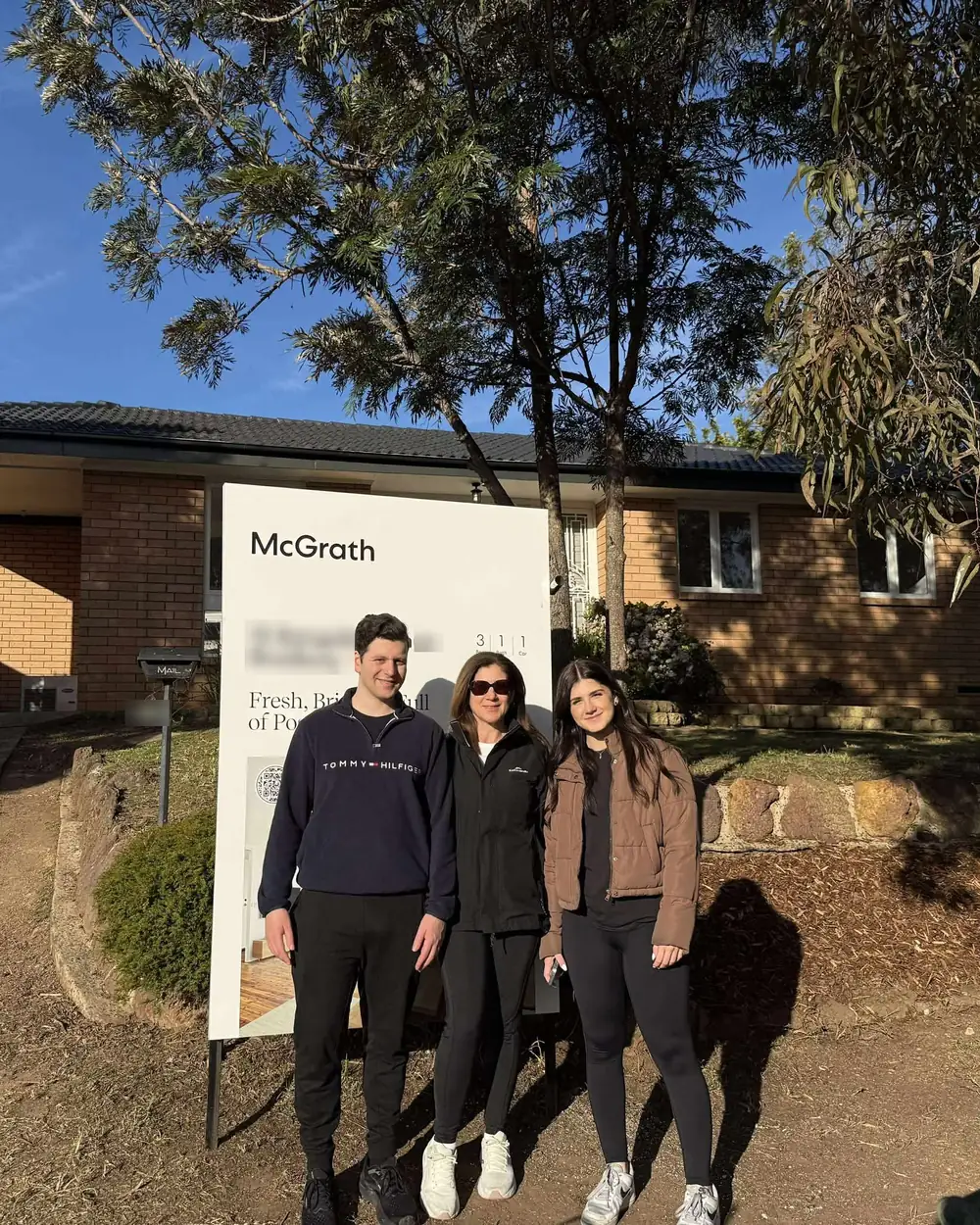 Three Links Property Finance clients in front of the agent&rsquo;s board at the home they bought
