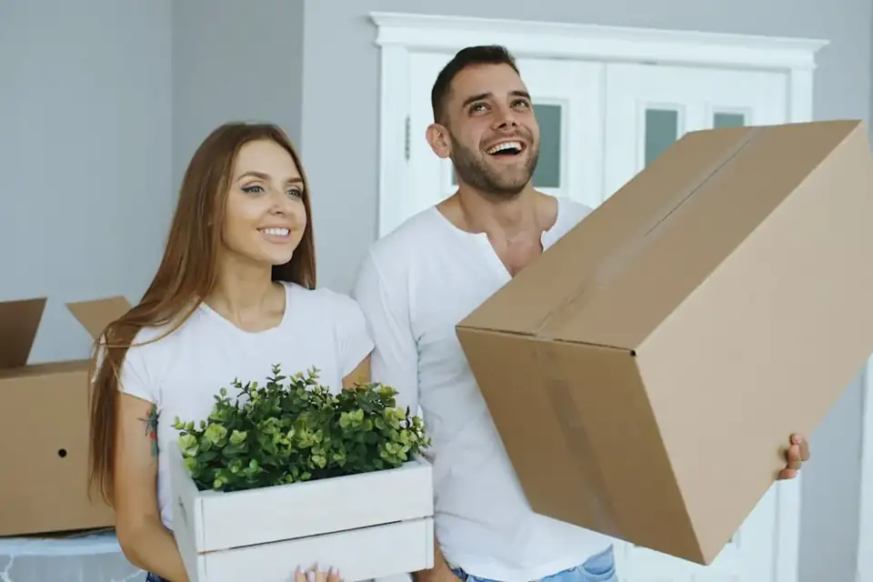 A couple carrying a box into their new home