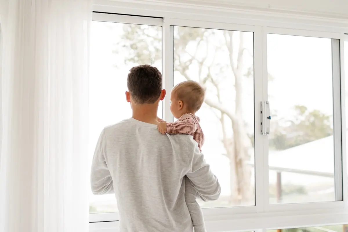A father holding a baby by the window