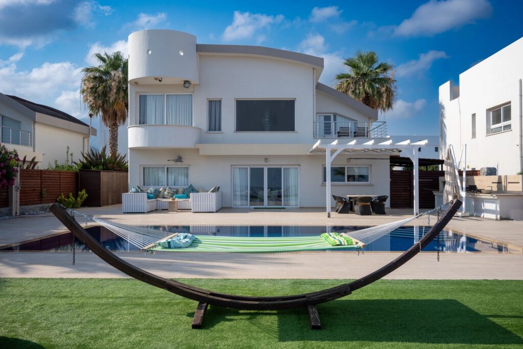 Horizontal Shot of a Relaxing Hammock and Beautiful White Villa with Pool